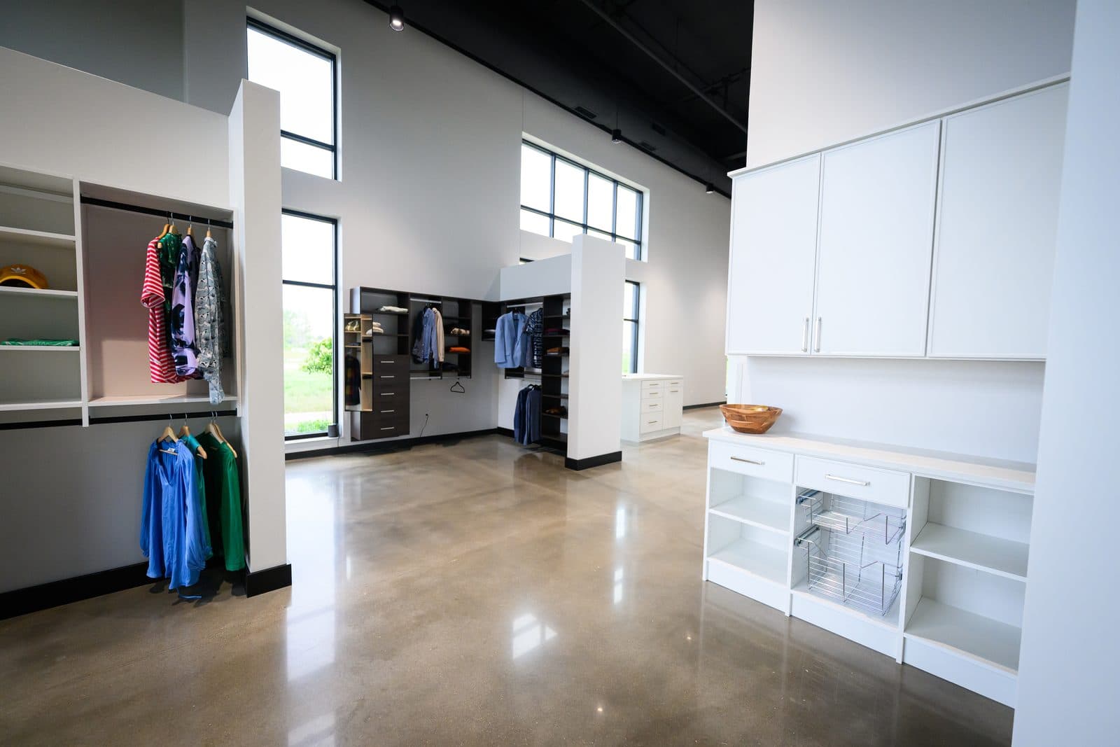 White cabinetry with pull-out wire baskets alongside light and dark closet displays in the Closet 1 Interiors showroom.