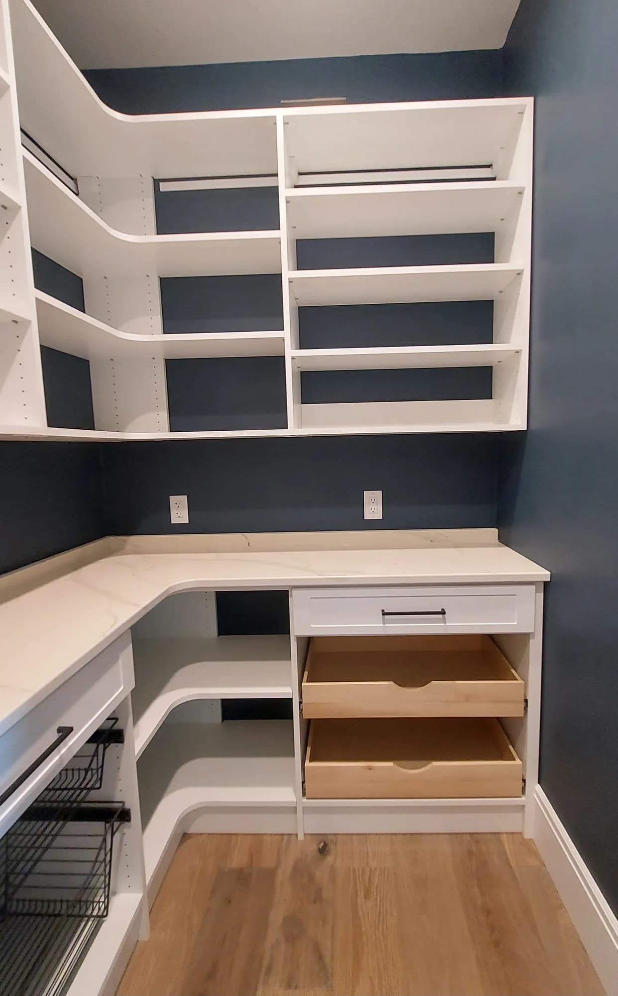 Utility room with a white counter, pull-out drawers and corner shelving against a navy wall