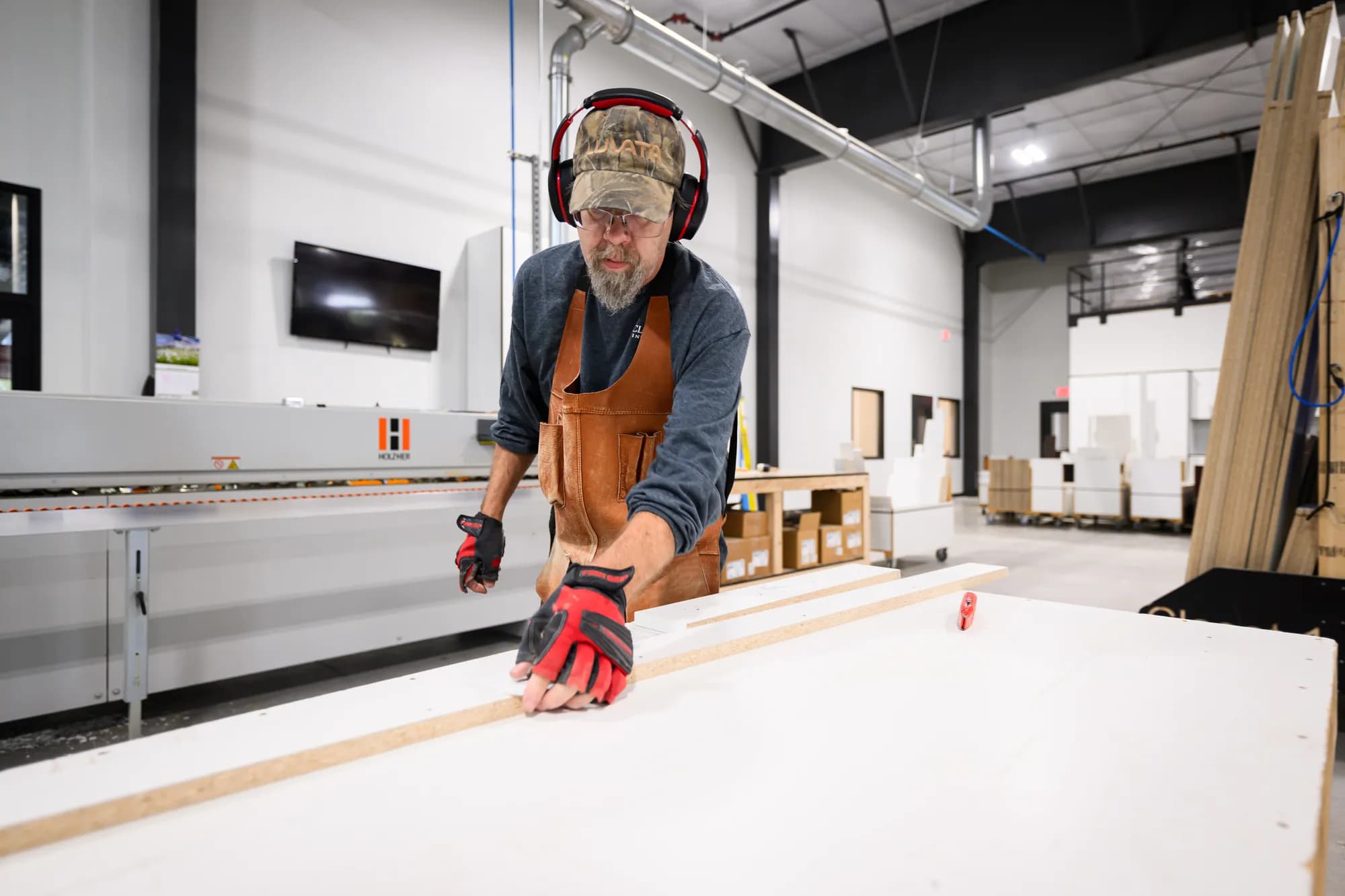 A Closet 1 craftsman guides a panel along the edge-banding line