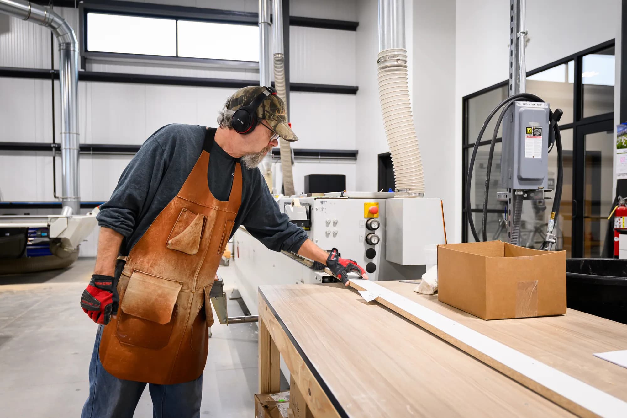 A Closet 1 craftsman feeds a closet panel through a saw in the Appleton facility