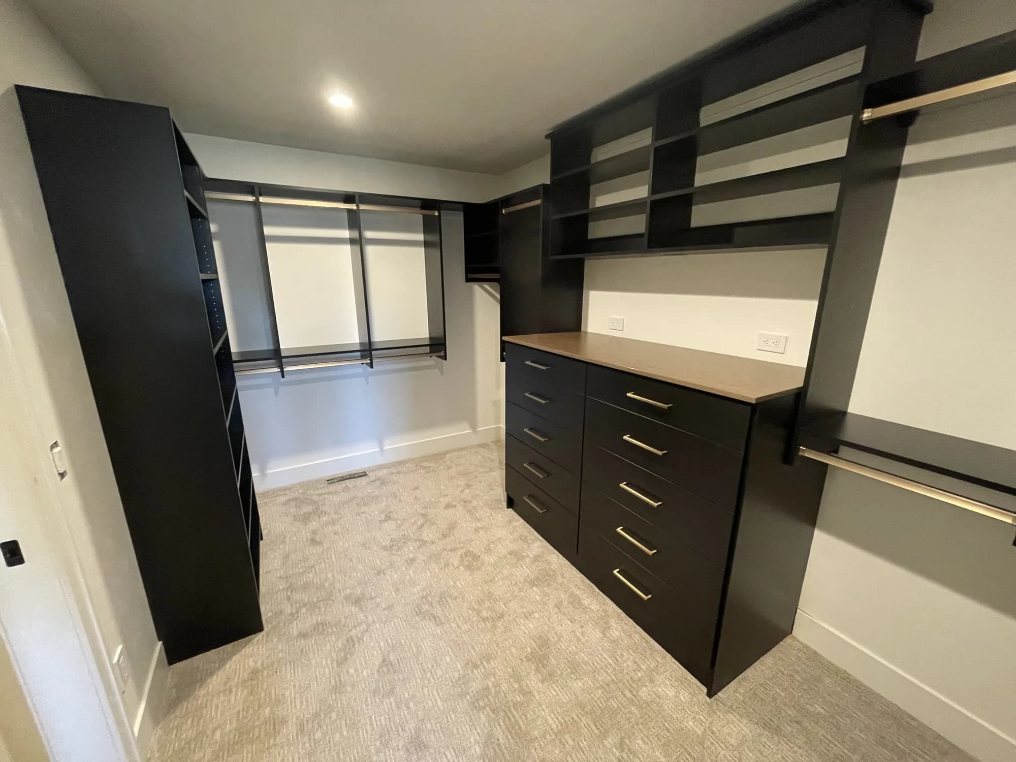 Walk-in closet with black tower storage and a drawer bank in a new home
